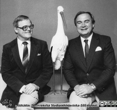 Kursledarna Nils Otto Sjöberg och Birger Åstedt vid en staty av en stork på kvinnokliniken i Lund 1984.
Foto från en samling funnen på KK i Lund hösten 2016 och tillvaratagen av en sekreteraren där (Elisabet Gyllander) i samband med att hon gick i pension. Hon överlämnade bilderna till Sydsvenska Medicinhistoriska Sällskapet där hon tyckte de passade bättre än hos henne.  
Nyckelord: Obstetrik;Gynekologi;Kurs;Kursledning;Lund;Universitetssjukhus;USiL;Professor