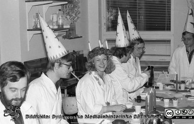 Fysiologiska Institutionen i Lund. Luciafest 1980. 
Fysiologiska Institutionen i Lund. Bildkälla: preparator Olle Hammar. Luciafest 1980. Lucia (Ingrid Lenninger), omgiven av sina stjärngossar bl.a. från vänster Lars Sjölin (ej med strut), Per-Olof Andersson och Per-Olof Grände och längst till höger David Gustafsson.
