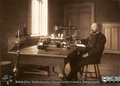 Professor Magnus Blix i sitt laboratorium på fysiologiska institutionen i Lund.
 Försök med grodmuskel 1899. Påskrift enligt Håkan Westling ("Tre professorer i fysiologi", 2003): Den. 31 dec 1899 kl: 10,45. Halfstor blek ungersk groda. G-muskel (gracilis) till indikatorn. Rumstemperatur 16,5°. Institutionen var då belägen på Biskopsgatan 5 i Lund
Nyckelord: Medicinska fakulteten;Lunds universitet;Institution;Laboratorium;Forskning;Vetenskap;Byggnad