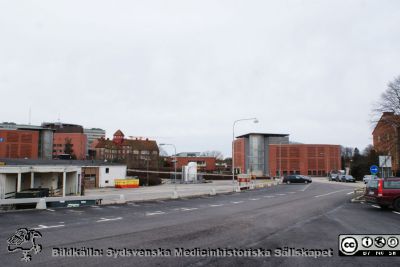 Universitetssjukhuset SUS Lund, mars 2012
Till vänster 1950-talets ambulansgarage (nu transportcentral) närmast kameran. Foto från Systervägen mot sydost. I bakgrunden från vänster parkeringshuset Ovalen, nya barnkliniken, Gamla Seminariet med toppigt torn (nu sjukhusadministration), personalmatsalen Paletten med medicinskt tekniska avdelningen (MTA) i källaren samt längst till höger parkeringshuset Kompassen och an liten del av sjuksköterskebostäderna vid Systervägen.
Nyckelord: Lasarettet;Lund;Logistik;Ambulansgarage;Administration;Avdelning;Medicinteknisk;Personalmatsal;Parkeringshus