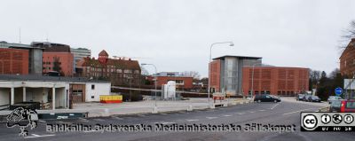 Lasarettet i Lund, mars 2012. 
Till vänster 1950-talets ambulansgarage (nu transportcentral) närmast kameran. Foto från Systervägen mot sydost. I bakgrunden från vänster parkeringshuset Ovalen, nya barnkliniken, Gamla Seminariet med toppigt torn (nu sjukhusadministration), personalmatsalen Paletten med medicinskt tekniska avdelningen (MTA) i källaren samt längst till höger parkeringshuset Kompassen och an liten del av sjuksköterskebostäderna vid Systervägen.
Nyckelord: Lasarettet;Lund;Logistik;Ambulansgarage;Administration;Avdelning;Medicinteknisk;Personalmatsal;Parkeringshus