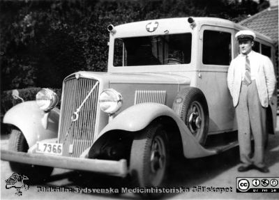 Ängelholms sjukhus.En ambulans med förare. 
Efter diabild i sjuksköterskan Lillie Börjessons samling från Ängelholms sjukhus.En ambulans med förare. Bilen ser ut som vore den från 1930-talet.
Nyckelord: Engelholm;Ängelholm;Ambulans;Ambulansförare