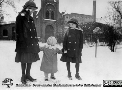 I lasarettsparken utanför kapellet tillhörigt patologiska instituionen i kv. Paradis
I lasarettsparken utanför kapellet tillhörigt patologiska institutionen i kvarteret Paradis. Från vänster Elsa Hultén (f. 1904, d. 1986, g. Catoni), Ingegerd Hultén (f. 1913, d. 2000; g. Hjortsberg) och Margit Hultén (f. 1905, d. 1992, g. Mattsson). I bakgrunden dåvarande panncentralen och maskinverkstaden. Foto c:a 1915.
Ur ett fotoalbum gjort av Johannes Hultén (1873-1951), verkmästare (elektricitet och röntgen) på Lasarettet i Lund. Bildkälla dotterdottern Viveka Rasmusson 2018.
Nyckelord: Lasarettet;Lund;Panncentral;Verkstad;Kapell;Patologisk;Institution;Park;Vinter