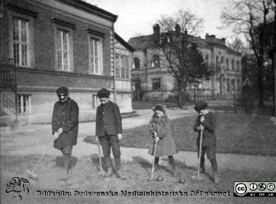 Barn leker i parken på södra lasarettsområdet (=kv Paradis). 
Flickan kan vara Margit Hultén. Foto i så fall i mitten på 1920-talet. Till vänster södra flygeln på 1899 års barnklinik, ännu bara envånings. Längre bort barnbördshuset från 1880-talet, ännu ej påbyggt.
Ur ett fotoalbum gjort av Johannes Hultén (1873-1951), verkmästare (elektricitet och röntgen) på Lasarettet i Lund. Bildkälla dotterdottern Viveka Rasmusson 2018.
Nyckelord: Barnsjukhus;Barnlek;Lasarettet i Lund;Sjukhuspark