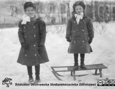 Elsa Hultén och Margit Hultén med kälke
Elsa Hultén och Margit Hultén med kälke  utanför intendenturhuset på Lasarettet i Lund, södra lasarettsområdet = kv. Paradis. Vinterbild. Foto c:a 1911.
Ur ett fotoalbum gjort av Johannes Hultén (1873-1951), verkmästare (elektricitet och röntgen) på Lasarettet i Lund. Bildkälla dotterdottern Viveka Rasmusson 2018.
Nyckelord: Lasarettet;Lund;Vinterbild;Intendenturhus;Kälke;Verkmästare;Röntgen;Verkstad