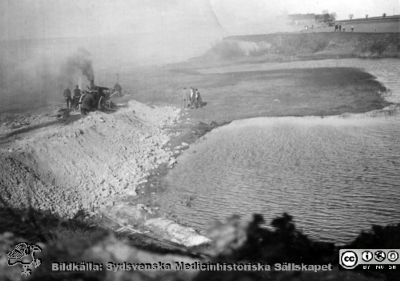 Medicinska avdelningen skall byggas på lasarettet i Lund
Medicinska avdelningen skall byggas på lasarettet. Den stod färdig 1918. Kanske visar bilden en ånglokomobildriven pump för att pumpa bort vatten ur den blivande husgrunden?
Ur ett fotoalbum gjort av Johannes Hultén (1873-1951), verkmästare (elektricitet och röntgen) på Lasarettet i Lund. Bildkälla dotterdottern Viveka Rasmusson 2018.
Nyckelord: Lasarettet;Lund;Medicinsk;Klinik;nglokomobil;Pump;Universitetssjukhus