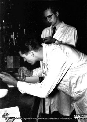 Kurslaboration på institutionen för medicinsk kemi i Lund 1957
Hans Frykman och Lars Nordmark (stående) vid en laboratoriebänk. Foto och bildkälla Sven Åke Hedström.
Nyckelord: Kurslaboration;Medicinsk kemi;Medicinsk;Fakultet;Lund