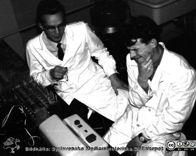 Kurslaboration på institutionen för medicinsk kemi i Lund 1957
Lars Nordmark och en kisande Sven Åke Hedström vid en fotometer som var svåravläst. Bildkälla Sven Åke Hedström.
Nyckelord: Medicinsk kemi;Fakultet;Institution;Lund;Kurslaboration