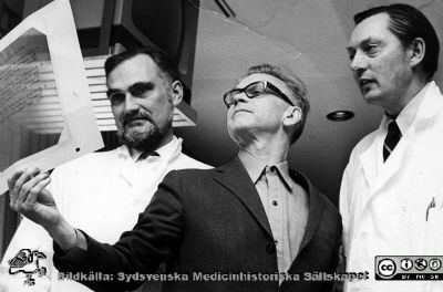 Ortopeden docent Håkan Brattström, reumatologen professor Kåre Berglund och handkirugen Lennart Mannerfelt.
Ortopeden docent Håkan Brattström, reumatologen professor Kåre Berglund och handkirugen Lennart Mannerfelt  studerar en gemensamt producerad overheadbild. Ur ortopedprofessorn Gunnar Wibergs bildsamling. Foto på 1960-talet. Publicerad på sidan 92 i Urban Rydholm: "Reumakirurgi- en knivig histgoria". Sydsvenska Medicinhistoriska Sällskapets årsskrift 2013, pp 91-105.
Nyckelord: Lasarettet;Lund;USiL;Universitetssjukhus;Ortopedisk;Kliniker;Reumatologisk