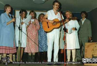 Ortopediska kliniken i Lund 1984. Julfest med undersköterrskan Bengt Nihlén på gitarr. Kör från vårdavdelning 1.
Från ortoped klin album 01, Lund. Fotograf Berit Jakobsson.  1984. Julfest med undersköterrskan Bengt Nihlén på gitarr, ortopedavdelningen 1. Kören har patientkläder. Längst till vänster Ann, senare gift med Bengt Nihlén.
Nyckelord: Lund;Universitetssjukhus;USiL;Kliniker;Ortopedi;Personal;Julfest;Fest;Musik;Gitarrer