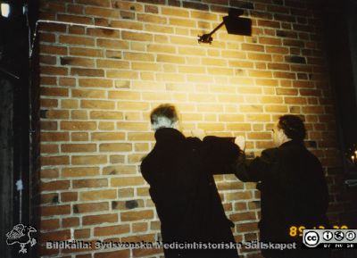Ortopediska kliniken i Lund11989.  Docent Göran Sundén (?)  och docent Lars Lidgren hjälps åt att sätta upp en minnestavla.
Från ortoped klin album 01, Lund. Fotograf Berit Jakobsson.  1989. En minnesplakett sätts upp på dåvarande ortopediska klinikens hus för att påminna om klinikens 75-årsjubileum. Huset tillkom 1929. Docent Göran Sundén (?)  och docent Lars Lidgren hjälps åt.
Nyckelord: Lund;Universitetssjukhus;USiL;Kliniker;Ortopedi;Läkare;Minnestavlor