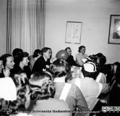 Kaffekalas, kanske på radiologiska kliniken i Lund. 
Mannen längst bort på andra sidan bordet finns också  på bilder med Martin Lindgren i samband med dennes disputation 1958. Kanske samkväm i samband med Martin Lindgrens disputation?
Nyckelord: Radiologisk;Onkologisk;Klinik;Fest;Disputation