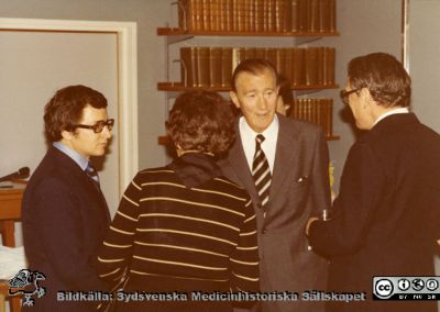 Urologiska klinikens 20-årsjubileum 1977. 
Från vänster Arne M. Olsson, Ellen Jönsson bakifrån (maka till Gösta Jönsson), professor Gösta Jönsson framför bokhyllan och docent Eric Lindstedt. 
Nyckelord: Lasarettet;Lund;Universitetssjukhuset;Urologiska;USiL;Kliniken;Kirurgisk