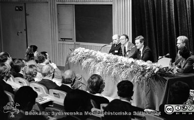 Forskningens Dag 1983 i Lund
Lasarettsfotograferna i Lund,  pärm  Sv/v Neg, 83:2. Forskningens Dag 1983 i Lund: "Cancerforskning - en nyckel til liv". Omärkt bild. I panelen, från vänster: professorerna Lars-Åke Fransson, Hans-Olof Sjögren, Dick Killander, Inge Olsson och Felix Mitelman. Sveriges kungapar, Drottning Siliva och kung Carl XVI Gustaf sitter främst i publiken. Från foto. 
Se också bild SMHS15227 från samma tillfälle.
Nyckelord: Lasarettet;Lund;Universitetssjukhuset;USiL;Forskningens Dag;Cancer