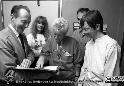 Docent Sören Nielzén och  bl.a. socionom Birgitta Lindahl
Lasarettsfotograferna i Lund.  Blandade negativ, omärkta år 1988-1995 (lösa negativhållare). 88-04-22. Psykiatrikern, docent Sören Nielzén, Psykiatriska kliniken avdelning 30. Här tillsammans med annan personal. Damen med de tre figurerna på tröjan vid dörren är socionom Birgitta Lindahl. Från negativ.
Nyckelord: Lasarettet;Lund;Universitetssjukhuset;USiL;Psykiatriska;Kliniken