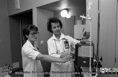 Efter 20 år tillbaka till jobbet
Lasarettsfotograferna i Lund.  Blandade negativ, omärkta år 1988-1995 (lösa negativhållare). 88-12-05. Medicinen avdelning 5. Efter 20 år, tillbaka till jobbet. Mona Svensson och Birgitta Jönsson, sjuksköterskor, vid infusionsaggregat. Från negativ.
Nyckelord: Lasarettet;Lund;Universitetssjukhuset;USiL;Medicinska;Kliniken;Personalvård