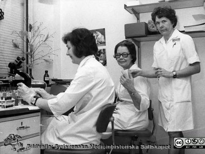 I mottagningens laboratorium på infektionskliniken i Lu nd
Album till Karl Emil Thulins 60-årsdag, 1975. Avdelningsföreståndaren på infektionsklinikens mottagning, syster Ann-Britt (i glasögon) tillsammans med två medarbetare, Ingar Widner och Signe (laboratorieassistenter?).

Nyckelord: Lasarettet;Lund;Universitetssjukhuset;USiL;Epidemiologiska;Kliniken;Infektion;Mottagning;Expedition;Arbetsrum