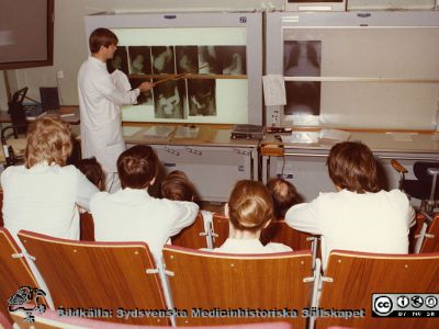 Röntgenrond med infektionsläkare i Lund ~1975
Foto ur album tillägnat professor Karl Emil Thulin på hans 60-årsdag, 1975.  Röntgenrond med infektionsläkare. Närmast kameran Ingrid Atterholms nacke och längst till höger Gunnar Kahlmeters. Bild SMHS15833 visar samma grupp tagen framifrån.
Nyckelord: Lasarettet;Lund;Universitetssjukhuset;USiL;Infektion;Kliniken;Röntgen;Rond