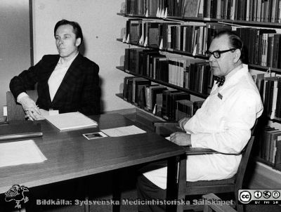 Sammanträde på biblioteket på infektionskliniken i Lund ~1975
Foto ur album tillägnat professor Karl Emil Thulin på hans 60-årsdag, 1975. Från vänster docent Carl Kamme och professor Karl-Emil Thulin. 
Nyckelord: Lasarettet;Lund;Universitetssjukhuset;USiL;Infektion;Kliniken;Sammanträde