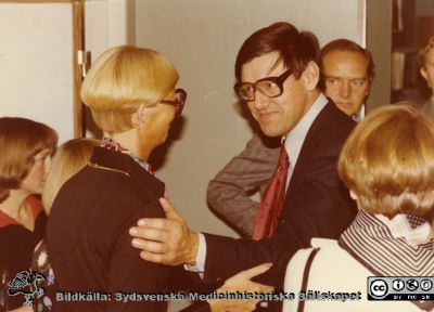 Urologiska klinikens 20-årsjubileum 1977
Professor Stig Bengmark hälsar på avdelsningsförestndaen Britt-Marie Andersson på centraloperationen på USiL. Bakom Bengmark skymtar professor Torsten Sundin. Bildkälla Eva Ljunggren. Samma negativ som bild SMHS12457.
Nyckelord: Lasarettet;Lund;Universitetssjukhuset;USiL;Urologiska;Kliniken