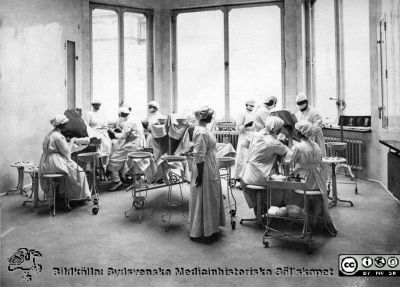 Kirurgens operationsavdelning sal 2 i Malmö
Påskrift:
Malmö allmänna sjukhus. Foto från 1920-talet (?)  Observera! Ingen takbelysning. Lanternin. Stavlampa vid fönstret. Operationen till vänster Doktor Löfberg. Patienten till vänster (vaken)  till höger eternarkos. 
Instrumentbordet hänger samman. 
Operation med två operationslag fram till år 1937. 
Foto: R. Küller, Malmö.
Nyckelord: Kirurgi;Operation;Malm;Allmänna;Sjukhus;MAS;Löfberg;Küller;Kapsel 09;Instrument;Sjuksköterska;Lanterning;Foto;1920-talet;1900-talet;1937