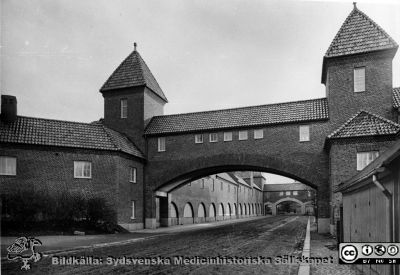 Valven över Allhelgona Kyrkogata nära 1918
Man ser de alldeles nybyggda valvbågar som är övergångar mellan södra och norra lasarettdelen. I valvbågar och vänstra längan var sydsvenska medicinhistoriska sällskapets samlingar inrymda i slutet på 1900-talet och som 2012 blev Livets Museum. Originalfoto. Monterat
Nyckelord: Kapsel 17;Lasarettet;Lund;Exteriörer;Allhelgona;Kyrkogata