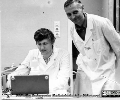 Neurologen Bengt Nilsson, sittande och gästforskaren Zbignev NN stående.
Ur professor Bo Siesjös fotoalbum 1964 - ~1992. Neurologen Bengt Nilsson, sittande och gästforskaren Zbignev NN stående.. Foto c:a 1970.
Nyckelord: Experimentell hjärnforskning;Neurologi.Medicinska fakulteten;Lunds universitet