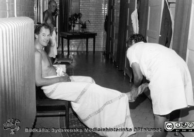 I sjukhusets badhus nära 1971
Ur yrkesdermatologen  Sigfrid Fregerts bildsamling från hud- och könskliniken i Lund och från yrkesdermatologin i Lund. Docent Sigfrid Fregert får sina fotsulor klappade av baderskan (fru Andersson?) på sjukhusbastun på Södra Lasarettsområdet; skönt och bra för cirkulationen. I bakgrunden skymtar röntgenologen Olle Norman. Foto nära 1971. Se också bl.a. bild SMHS14408. Foto.
Nyckelord: Lasarettet;Lund;Universitetssjukhuset;USiL;Hud- och könsklinik;Dermatologisk;Venerologisk;Bastu