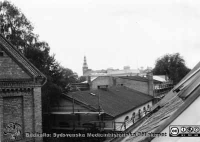 Utsikt  på 1960-talet från hudklinikens vindsfönster västerut
Ur yrkesdermatologen Sigfrid Fregerts bildsamling från hud- och könskliniken i Lund och från yrkesdermatologiska avdelningen i Lund. Utsikt  på 1960-talet från hudklinikens vindsfönster västerut mot Palaestra, universitetsbyggnaden, och hyreshuset med ett högt torn vid Kyrkogatan.  Från originalfoto.
Nyckelord: Lasarettet;Lund;Universitetssjukhuset;USiL;Hud- och könsklinik;Hud;Klinik;Dermatologisk;Venerologisk