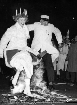 Lucia1956
Hans Hammars fästmö, Lucian Ingalill Rudin hoppar rituellt över en öppen brasa på universitetsparken med Rector Magnificus Ragnar Bergendahl.
Nyckelord: Lucia;Fest;Lunds universitet;Akademiska Föreningen i Lund;Ritual