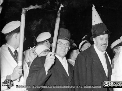 Luciatåg 13/12 1956
Docent David Ingvar och laboratorn i fysiologi Gunnar Lundin som uppsluppna fackelbärare i doktorshattar.
Nyckelord: Luciatåg;Fest;Akademiska Föreningen i Lund;Lunds universitet;Fackeltåg;Västsvenska nationerna