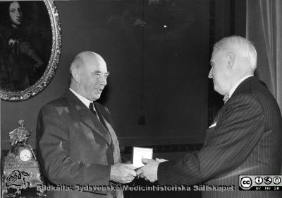 Ragnar Bergendal överlämnar den 17 november 1955 universitetets minnesmedalj av år 1918 till nyligen avgångne överbibliotekarien Gunnar Carlquist
Universitetets rektor, professor Ragnar Bergendal, överlämnar den 17 november 1955 universitetets minnesmedalj av år 1918 till överbibliotekarien Gunnar Carlquist, till höger. Denne avgick sommaren 1955. Bildkälla AF:s arkiv i Lund, bilderbok 50, 1955.
Nyckelord: Hedersbevis;Minnespeng;Lunds universitet;Rector Magnificus