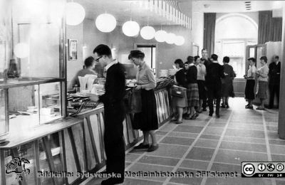 Serveringsdisken på Ateneum ("Atén") i Lund,  våren 1959. 
Vin och sprit fick inte säljas här. Sådant fick privatpersoner eller enskilda slutna sällskap ordna själva.
Nyckelord: Akademiska föreningen;Ateneum;Atén;Lunds universitet;Servering;Mjölkbar