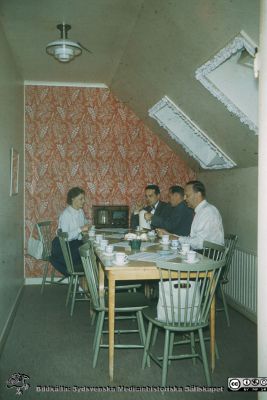 Kaffepaus på gamla lasarettskontoret 1960
Kaffepaus under takåsen i administrationsbyggnaden vid portvaktshuset vid Allhelgona Kyrkogata. Samma fototillfälle som SMHS251_000_01. Påskrift på den bilden: "Bengt Lundquist, Lennart Pihlquist, Erik Nilsson". Namnen gäller för den högra radens personer . Foto 1960, rimligen inför administrationens flytt till norra lasarettsområdet bara något senare.
Nyckelord: Lasarettet;Lund;Unisversitssjukhuset;USiL;Administration;Kafepaus;Pausrum