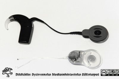 Hörapparat för cochleaimplantat
Istället för att som en vanlig hörapparat förstärka ljudet vid ytterörat kan man idag operera in ett implantat som levererar ljud i form av elektriska signaler direkt till hjärnan, via hörselnerven. Här modellen Nucleus 6 från företaget Cochlear. Ingick i en medicinhistorisk utställning om hörsel och hörapparater på Livets Museum i Lund 2013. Från Kulturen i Lund.
Nyckelord: Hörapparat;Uställning;Livets Museum;SMHS;Sydsvenska Medicinhistoriska Sällskapet