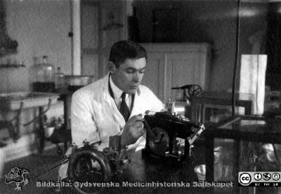 Fotoalbum tillägnat Professor Torsten Hellman Från Tacksamma Lärjungar 3.4.1924. 
Fotoalbum tillägnat Professor Torsten Hellman Från Tacksamma Lärjungar 3.4.1924. 
Bildtext: "Sven Johansson". 
Han sitter vid en laboratoriebänk med två olika mikrotomer för att skära snitt att montera på objektsglas för senare färgning.
Nyckelord: Histologiska avdelningen;Anatomiska Institutionen;Locus Medicus Lundensis;Medicinska fakulteten i Lund;Universitet;Kurslaboration