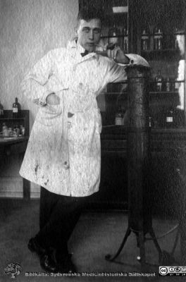 Fotoalbum tillägnat Professor Torsten Hellman Från Tacksamma Lärjungar 3.4.1924. 
Fotoalbum tillägnat Professor Torsten Hellman Från Tacksamma Lärjungar 3.4.1924. 
Bildtext: "Einar Andersson".
Senare känd som dugande konstnär som signerade sina verk med en sjua (7). Han var en av studenttidningen Lundagårds dittills bästa tecknare. Blev efter utbildningen i Lund ögonläkare i Halmstad och slutade som överläkare på lasarettet där. På bilden står han stödd på en gastub, rimligen innehållande koldioxid som man använde för att frysa preparat vid snittning i frysmikrotom.
Nyckelord: Histologiska avdelningen;Anatomiska Institutionen;Medicinska fakulteten i Lund;Locus Medicus Lundensis