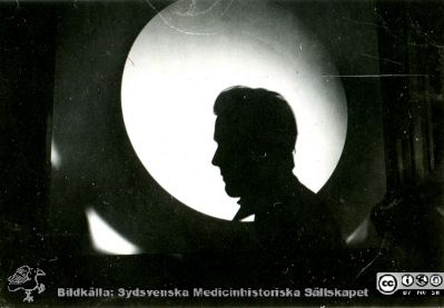 1928 års kurs i histologi i Lund
Fotoalbum märkt Histologikursen anno 1928. 
Detta album innehåller bilder från dåvarande histologiska avdelningen på anatomiska institutionen i Lund på Biskopsgatan 7. Liksom de övriga i serien skapades det av kursdeltagarna och tillägnades kursledaren professor Torsten Hellman som uppskattning av hans lärargärning. Bildtext  "Koch" (dvs Fredrik Koch i senare tids stavning) i siluett mot projektionsmikroskopets ljusa skiva. 
Bildkälla Stiftelsen Locus Medicus Lundensis 250317.
Nyckelord: Locus Medicus Lundensis;Medicinska fakulteten i Lund;Histologiska avdelningen;Sydsvenska Medicinhistoriska Sällskapet;SMHS;Anatomiska Institutionen;Studenter;Lärare