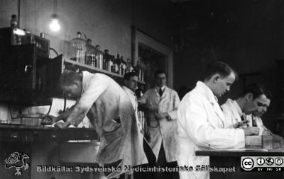 1928 års kurs i histologi i Lund
Fotoalbum märkt Histologikursen anno 1928. 
Detta album innehåller bilder från dåvarande histologiska avdelningen på anatomiska institutionen i Lund på Biskopsgatan 7. Liksom de övriga i serien skapades det av kursdeltagarna och tillägnades kursledaren, professor Torsten Hellman, som uppskattning av hans lärargärning. Bildtext saknas. Studenterna tillverkar troligast preparat på objektglas för mikroskopiering. Ser ut att vara samma personer som i bild i fil imgLA2250318ff104.
Bildkälla Stiftelsen Locus Medicus Lundensis 250317.
Nyckelord: Locus Medicus Lundensis;Medicinska fakulteten i Lund;Histologiska avdelningen;Sydsvenska Medicinhistoriska Sällskapet;SMHS;Anatomiska Institutionen;Studenter;Lärare