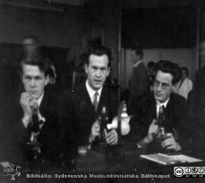 Bild i fotoalbum  tillägnat professor Torsten Hellman från deltagarna i histologikursen ht 1930. 
Fotoalbum  "TILL PROFESSOR TORSTEN hELLMAN MED TACK FRÅN DELTAGARNA I HISTOLOGIKURSEN HÖSTTERMINEN 1930".  Bildtext "Ryde, Lewis-Johnson, Lofter".  Foto troligen i mirkoskoperingssalen.
Bildkälla stiftelsen Locus Medicus Lundensis och Sydsvenska Medicinhistoriska Sällskapet / SMHS. Fotograf okänd.
Nyckelord: Histologiska avdelningen;Anatomiska Institutionen;Entrétrappa;Medicinska fakulteten i Lund;Sydsvenska Medicinhistoriska Sällskapet;Locus Medicus Lundensis;Eleve