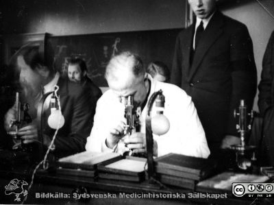 Fotoalbum "Kursen i histologi H T 1932.
Fotoalbum "Kursen i histologi H T 1932". Bildtext "Chefen".  Professor Torsten Hellman demonstrerar i ett kursmikroskop på histologiska avdelningens mikroskoperingssal på anatomiska institutionen i Lund. 
Bildkälla stiftelsen Locus Medicus Lundensis och Sydsvenska Medicinhistoriska Sällskapet / SMHS. Fotograf okänd. 
Nyckelord: Medicine studerande;Histologiska avdelningen;Anatomiska Institutionen;Medicinska fakulteten i Lund;Locus Medicus Lundensis;Universitetet i Lund