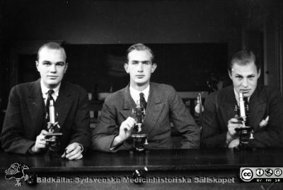 Fotoalbum "Kursen i histologi H T 1932.
Fotoalbum "Kursen i histologi H T 1932". Bildtext "Anquist(eller Amquist?), Willert, Bohm.".  Troligen tre medicine studerande vid  kursmikroskop på histologiska avdelningens mikroskoperingssal på anatomiska institutionen i Lund. 
Bildkälla stiftelsen Locus Medicus Lundensis och Sydsvenska Medicinhistoriska Sällskapet / SMHS. Fotograf okänd.
Nyckelord: Medicine studerande;Histologiska avdelningen;Anatomiska Institutionen;Medicinska fakulteten i Lund;Locus Medicus Lundensis;Universitetet i Lund