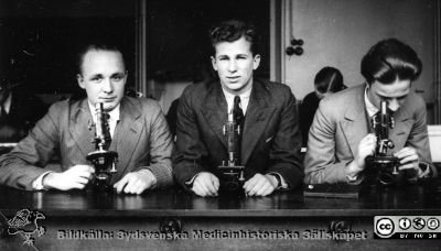 Fotoalbum "Kursen i histologi H T 1932.
Fotoalbum "Kursen i histologi H T 1932". Bildtext "Smitt, Håkan Nilsson, Ståhl".  Troligen tre medicine studerande vid  kursmikroskop på histologiska avdelningens mikroskoperingssal på anatomiska institutionen i Lund. 
Bildkälla stiftelsen Locus Medicus Lundensis och Sydsvenska Medicinhistoriska Sällskapet / SMHS. Fotograf okänd.
Nyckelord: Medicine studerande;Histologiska avdelningen;Anatomiska Institutionen;Medicinska fakulteten i Lund;Locus Medicus Lundensis;Universitetet i Lund