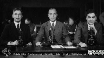Fotoalbum "Kursen i histologi H T 1932.
Fotoalbum "Kursen i histologi H T 1932". Bildtext "Belfrage, Rydén, Herner".  Troligen tre medicine studerande vid  kursmikroskop på histologiska avdelningens mkroskoperingssal på anatomiska institutionen i Lund. 
Bildkälla stiftelsen Locus Medicus Lundensis och Sydsvenska Medicinhistoriska Sällskapet / SMHS. Fotograf okänd.
Nyckelord: Medicine studerande;Histologiska avdelningen;Anatomiska Institutionen;Medicinska fakulteten i Lund;Locus Medicus Lundensis;Universitetet i Lund