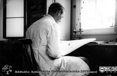 Fotoalbum  "Kursen i histologi H T 1932.
Fotoalbum  "Kursen i histologi H T 1932".  Bildtext "Laborationsteknik". Den streckade linjen pekar på tidningen Sydsvenskan i knäet på mannen i fläckad laboratorierock. Bilden kan också ses som en fortsättning på bildserien "Sällskapsliv". Troligen medicinare under studier på histologiska avdelningens mikroskoperingssal på anatomiska institutionen i Lund. 
Bildkälla stiftelsen Locus Medicus Lundensis och Sydsvenska Medicinhistoriska Sällskapet / SMHS. Fotograf okänd.
Nyckelord: Universitetet i Lund;Locus Medicus Lundensis;Anatomiska Institutionen;Histologiska avdelningen;Sydsvenska Medicinhistoriska Sällskapet;SMHS;Medicine studerande;Laboration