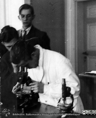 Fotoalbum "Kursen i histologi V. T. 1933.
Fotoalbum "Kursen i histologi V. T. 1933. Bildtext: "Wide kapten löjtnant". Troligast en amanuens, demonstrerande något i ett mikroskop på avdelningen för histologi på anatomiska institutionen i Lund. 
Bildkälla stiftelsen Locus Medicus Lundensis och Sydsvenska Medicinhistoriska Sällskapet / SMHS. Fotograf okänd.
Nyckelord: Locus Medicus Lundensis;Medicinska fakulteten i Lund;Histologiska avdelningen;Medicinska fakulteten i Lund;Sydsvenska Medicinhistoriska Sällskapet;Anatomiska Institutionen;Studenter;Amanuenser