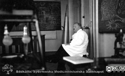 Fotoalbum  tillägnat Professor Torsten Hellman av lärjungarna 1935. Bildtext saknas. Profesorn i en paus i sitt föreläsande . De svarta tavlorna är fulla med text och enkla skiser. Kursen är för medicine studerande på avdelningen för histologi på anatomiska institutionen i Lund. 
Bildkälla stiftelsen Locus Medicus Lundensis och Sydsvenska Medicinhistoriska Sällskapet / SMHS. Fotograf okänd.
Nyckelord: Histologiska avdelningen;Anatomiska Institutionen;Sydsvenska Medicinhistoriska Sällskapet;Medicinska fakulteten i Lund;Locus Medicus Lundensis;Medicine studerande;Lunds universitet
