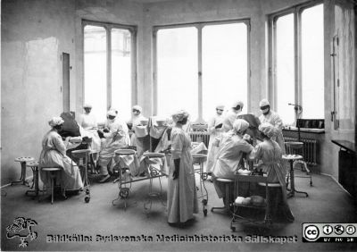 Malmö allmänna sjukhus. Foto från 1920-talet (?)  Kirurgens operationsavdelning sal 2. 
Operationssal på Malmö Allmänna Sjukhus. Repro från vykort utgivet av Malmö Allmänna Sjukhus vid dess 100-årsjubileum 1996. Bildkälla Karin Lindholm, Limhamn. Samma bild som SMHS3395. Påskrift på den bilden: 
Malmö allmänna sjukhus. Foto från 1920-talet (?)  Kirurgens operationsavdelning sal 2. Observera! Ingen takbelysning. Lanternin. Stavlampa vid fönstret. Operationen till vänster Doktor Löfberg. Patienten till vänster (vaken)  till höger eternarkos. 
Instrumentbordet hänger samman. 
Operation med två operationslag fram till år 1937. 
Foto: R. Küller, Malmö. 
Nyckelord: Kirurgi;Operation;Malm;Allmänna;Sjukhus;MAS;Löfberg;Küller;Kapsel 09;Instrument;Sjuksköterska;Lanterning;Foto;1920-talet;1900-talet;1937