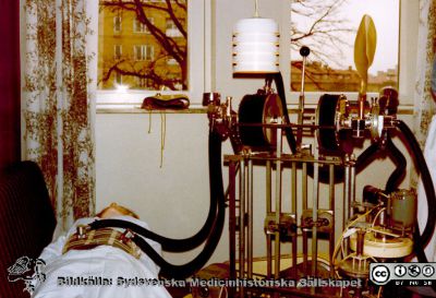 En Lundiarespirator på en utställning på Malmö Allmänna Sjukhus 1980
Foto från en utställning om respiratorvård vid 100-årsjubileet för infektionskliniken i Malmö 1980. Utställningen stod i anslutning till sjukhusets personalmatsal. Apparaten är en Lundiarespirator med två bälgar som utprovades på 1950-talet på kliniken- Den ena bäljgen driver ett s.k. Jacksonbälte som trycker ihop bröstkorg och buk för att hjälpa patienten med utandning. Den andra dirver intubationsandning. Sköterskans uniform är typisk för 1950-talets lundautbildade SSSH-sköterskor, med mössa och hakband.Bildkälla Klas Ramnerö 2014.
Nyckelord: UMAS;MAS;Infektionsklinik;Respirator;Malm;Allmänna;Sjukhus