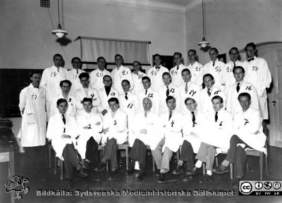 Medicinarkursen i kirurgi i Lund höstterminen 1953
Medicinarkursen i kirurgi i Lund höstterminen 1953. Professor Philip Sandblom i främre radens mitt. 1: Claes Lundgren. 2: Lars Bjersing, senare patolog i Umeå, 3: Sven Melander. 4: Arne Brun, senare neuropatologprofessor i Lund. 5: Carl Erik Svenheden, 6: Arne Norman, senare klinisk kemist i Stockholm, 7: Kjell Wallenius, 8: Olle Sundquist (Sundström?) 9: Bengt Lindskog, kirurg och medicinhistoriker i Köpenhamn, 10: Olle Sundström? / Bengt ? Odeberg? 11: Nils Tryding, senare klinisk kemist i Kristianstasd, 12: Gert Vladis / Wladis, 13: Jan Söderström 14: Bengt Elmfors. 16: Rolf Håkansson.  17: Ingemar Erici, senare gynekolog i Malmö, 18: doc Gösta Jönsson, senare professor i Lund, 19: doc Stig Borgström, 20:  Sommar "Acke" Bruzelius. 21. Sten (Håkan??) Brattström.  22: L. E. "Charlie" Gelin, senare transplantationskirurg i Göteborg, 23: Carl Axel Ekman, senare kirurg i Borås, 24: Göran Lundh, senare kirurg på Södersjukhuset i Stockholm, 25: Lennart Iacobeus, nr 26 Lars Röhl, senare professor i urologi i Heidelberg i Tyskland, nr 27 Arne M. Olsson, senare kirurg i Västerås?, nr 28: doc Lennart Andersson, senare professor i Umeå och Stockholm.
Nyckelord: Lasarett;Lund;Universitet;Universitetssjukhus;USiL;Kirurgi;Kurs;Utbildning;Medicine;Kandidat;Studerande;Studenter